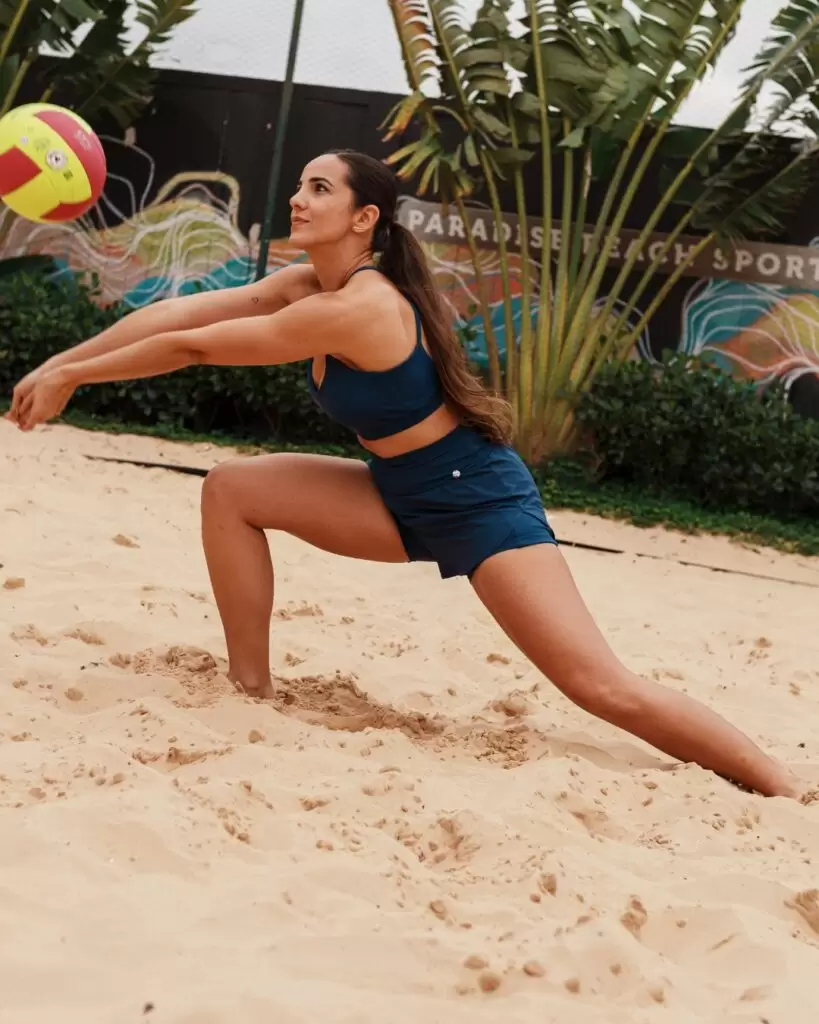 mulher usando roupa fitness azul para beach tennis na areia